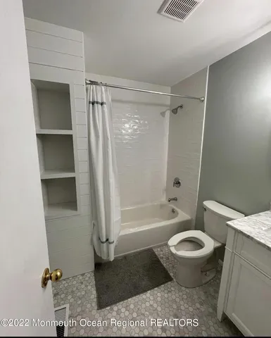 a bathroom with a granite countertop toilet and a shower
