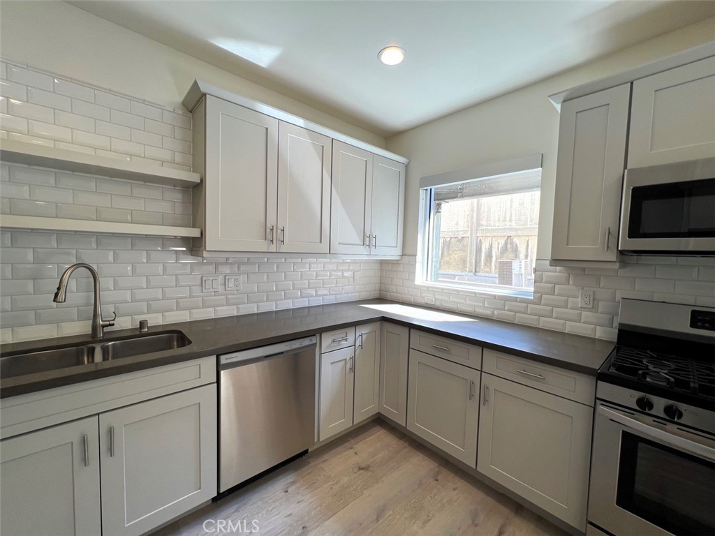 a kitchen with stainless steel appliances granite countertop white cabinets a sink and a stove