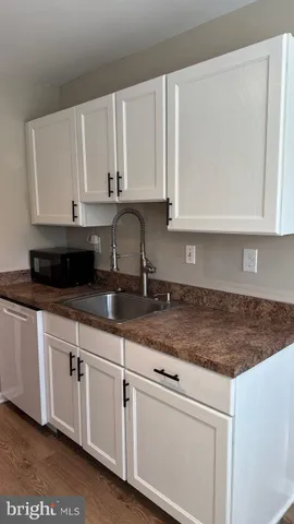 a kitchen with granite countertop white cabinets and a sink