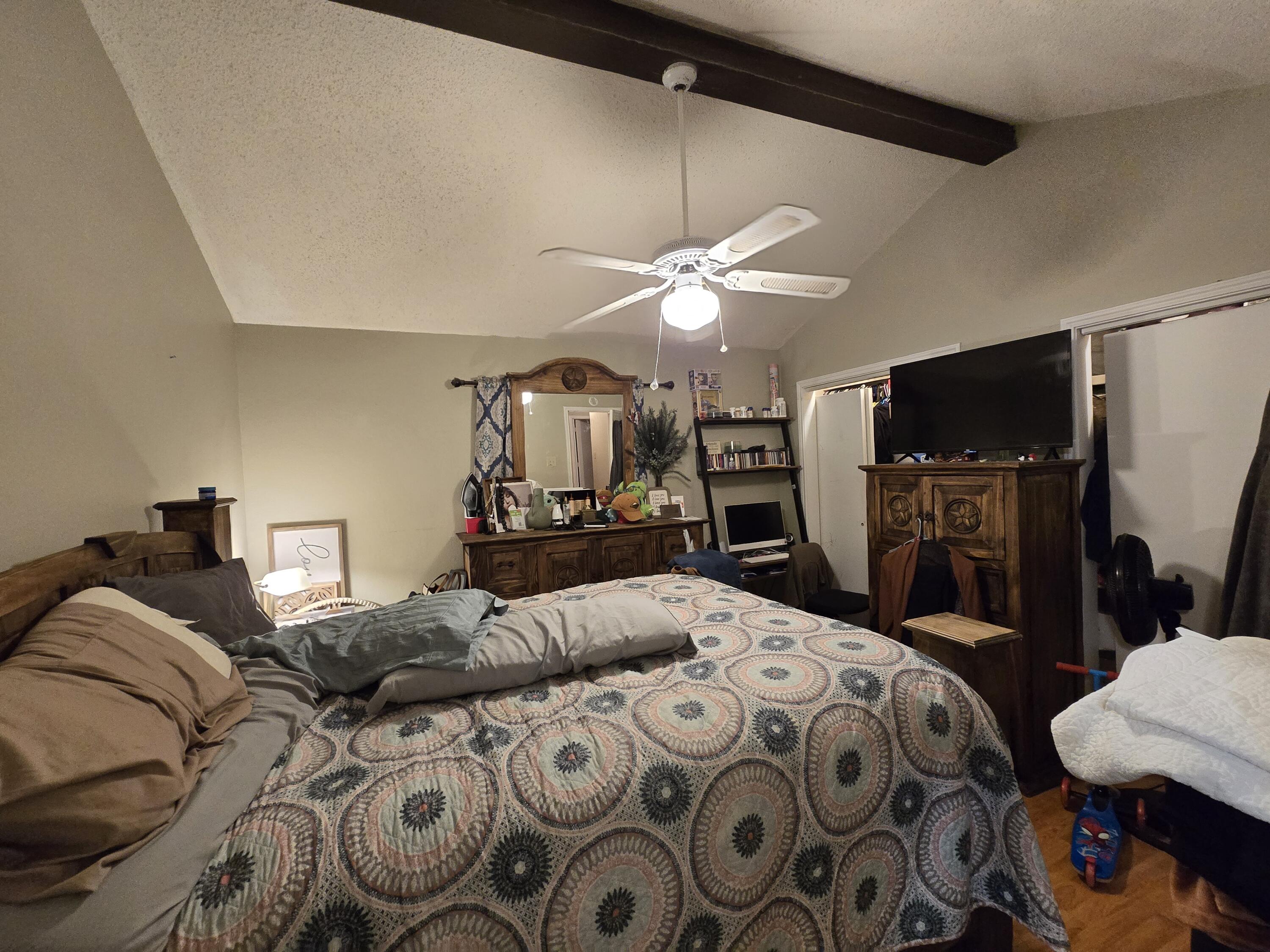 5806 12th Street Lubbock, TX 79416 - Photo 12 of 17 a bedroom with a bed a chandelier and a flat tv screen on a dresser