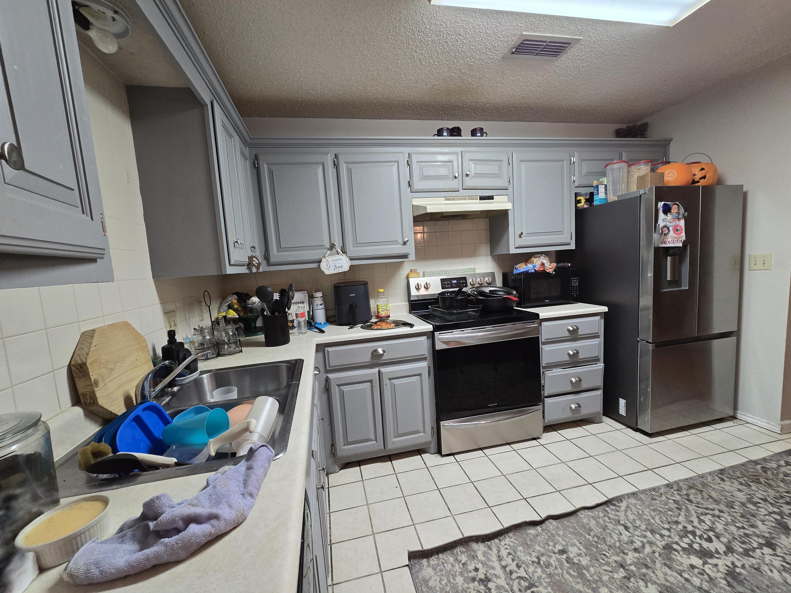 5806 12th Street Lubbock, TX 79416 - Photo 6 of 17 a kitchen with a refrigerator sink and cabinets