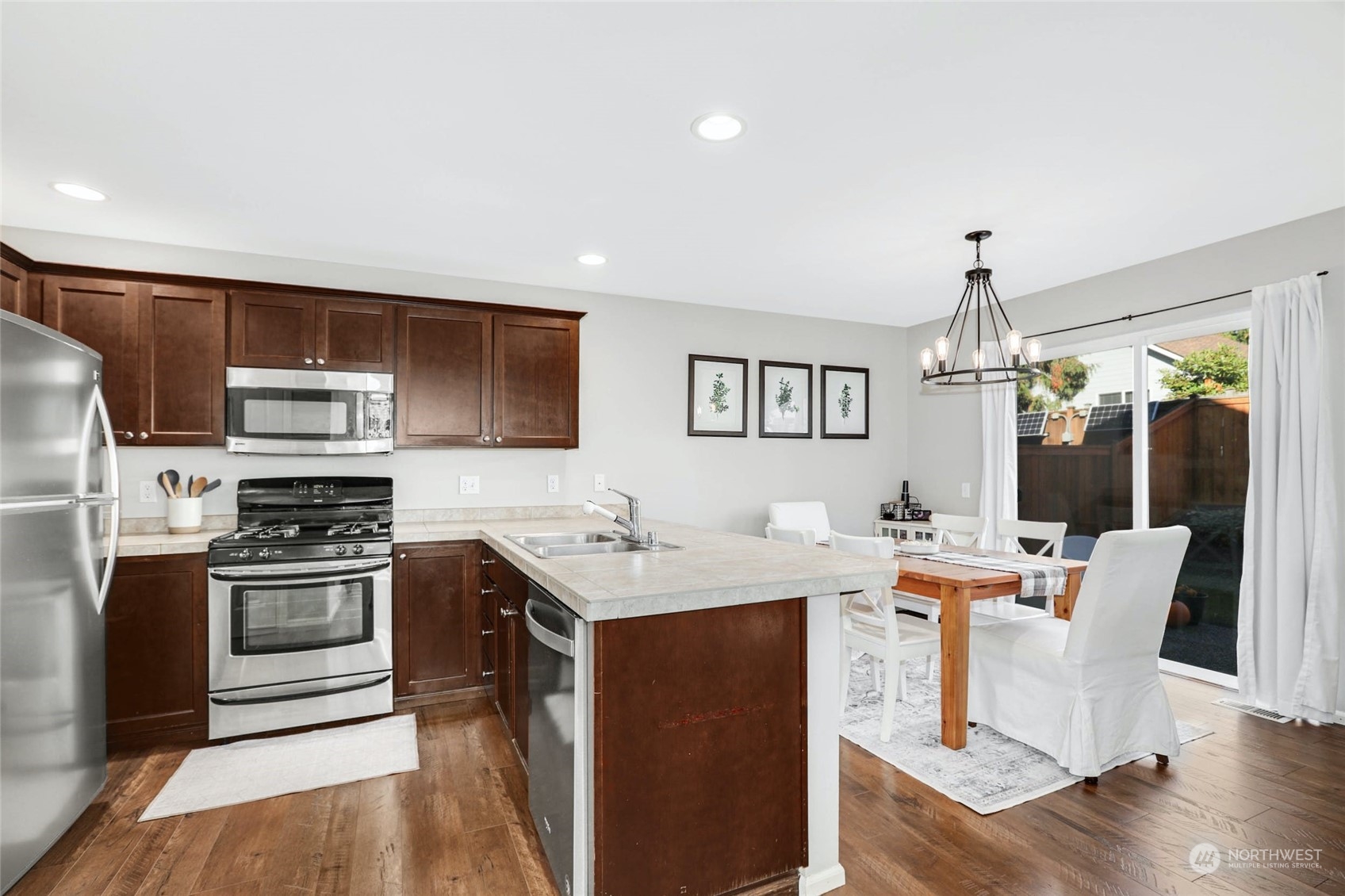 15 194th Street Southwest Bothell, WA 98012 - Photo 11 of 27 a open kitchen with stainless steel appliances granite countertop a stove top oven a sink dishwasher a dining table and chairs with wooden floor