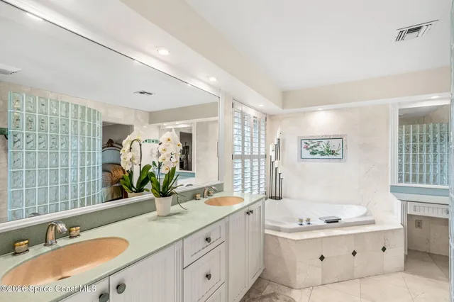 a bathroom with a granite countertop double vanity sink a mirror and a bathtub