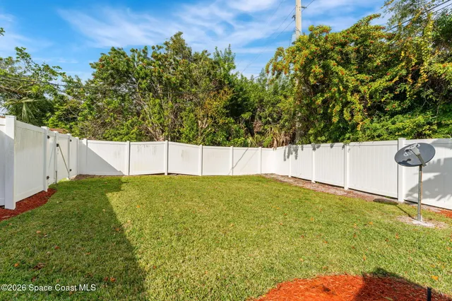 a backyard of a house with table and chairs plants and a barbeque