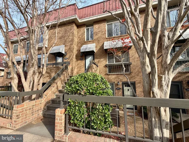 a view of a brick house with a small yard and wooden fence