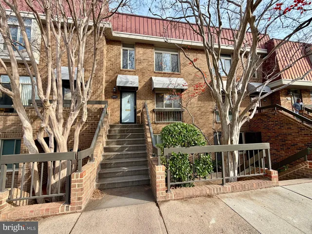 a front view of a house with glass windows and a tree