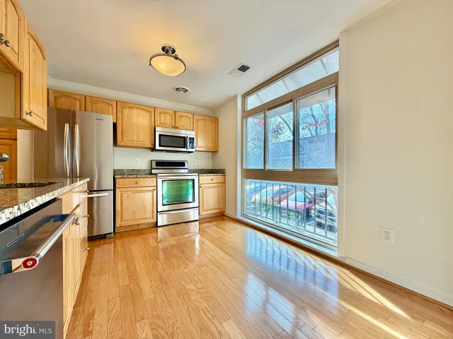 a open kitchen with wooden floors and stainless steel appliances