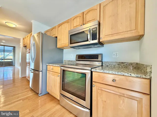 a kitchen with granite countertop a stove microwave and refrigerator