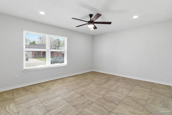 an empty room with windows and fan