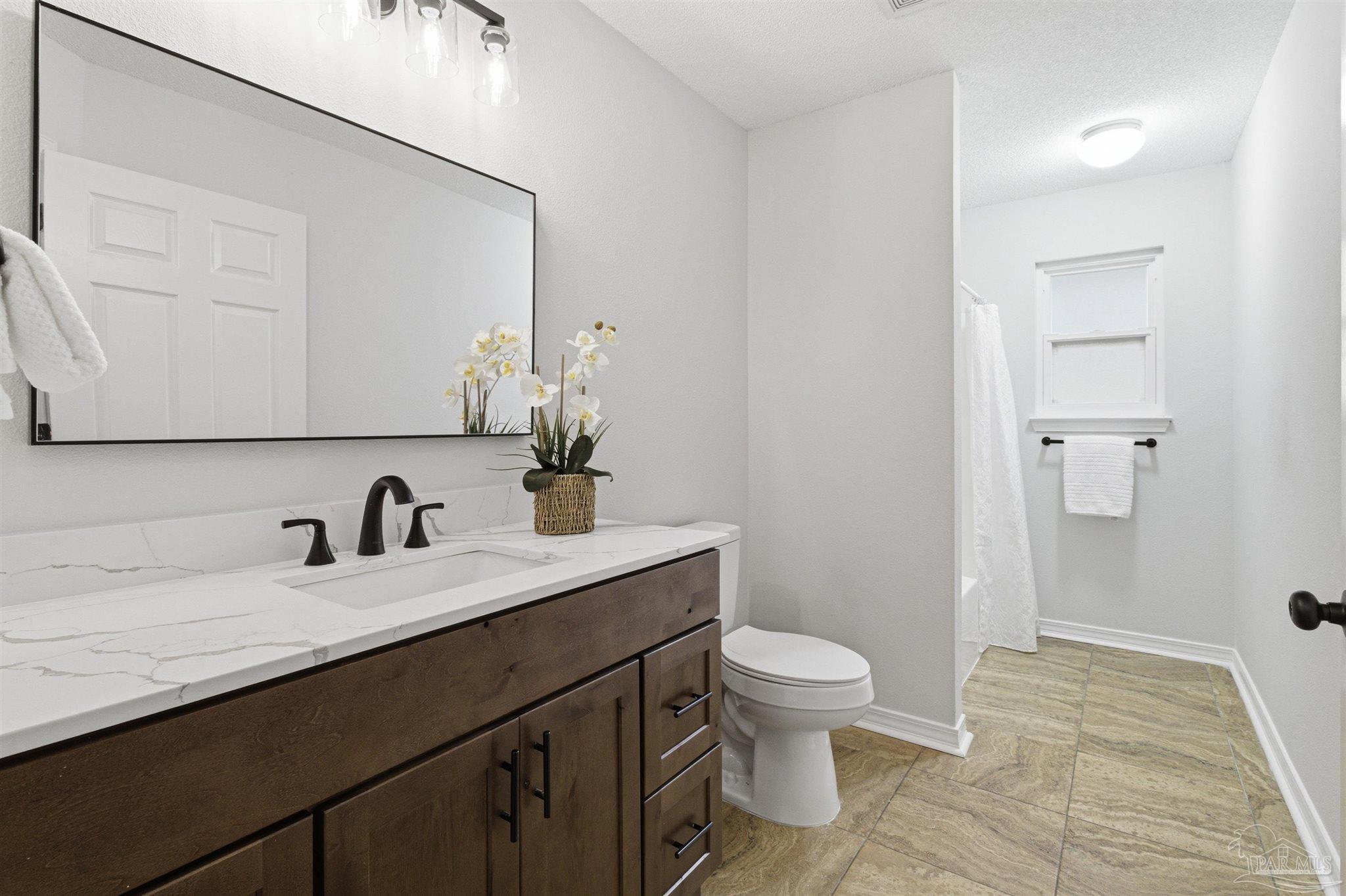 1866 Wareham Way Cantonment, FL 32533 - Photo 17 of 33 a bathroom with a granite countertop sink a toilet and a mirror