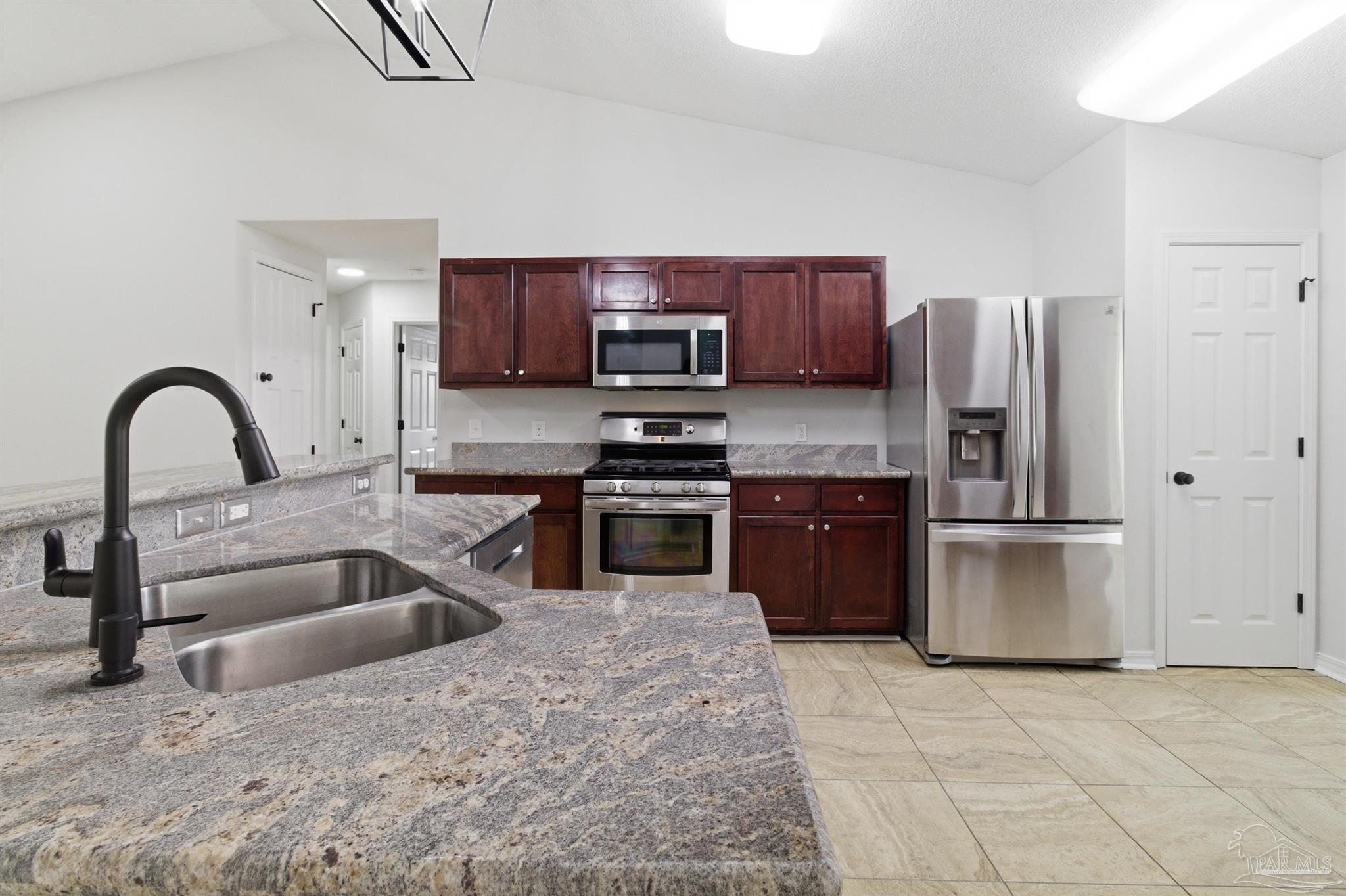 1866 Wareham Way Cantonment, FL 32533 - Photo 2 of 33 a kitchen with stainless steel appliances granite countertop a refrigerator a stove a sink and a stove with wooden floors