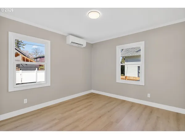 a view of an empty room with a window and wooden floor