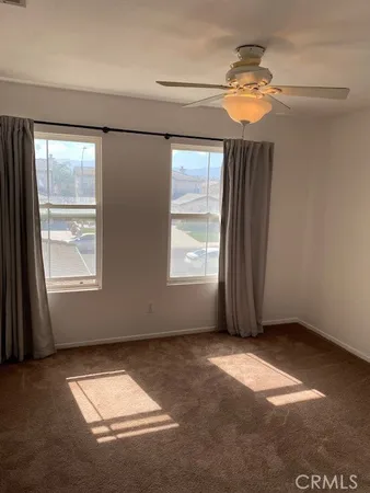an empty room with windows and chandelier fan
