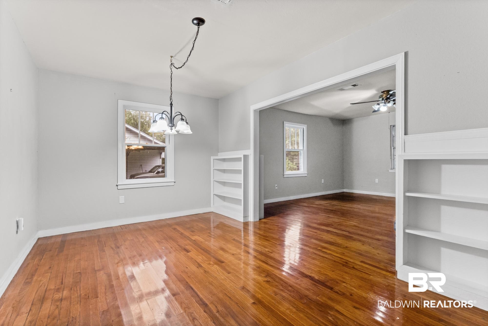 312 Sutherland Drive Mobile, AL 36611 - Photo 8 of 28 Unfurnished dining area with wood flooring throughout a room featuring a chandelier, built-in shelving, and a wide entryway
