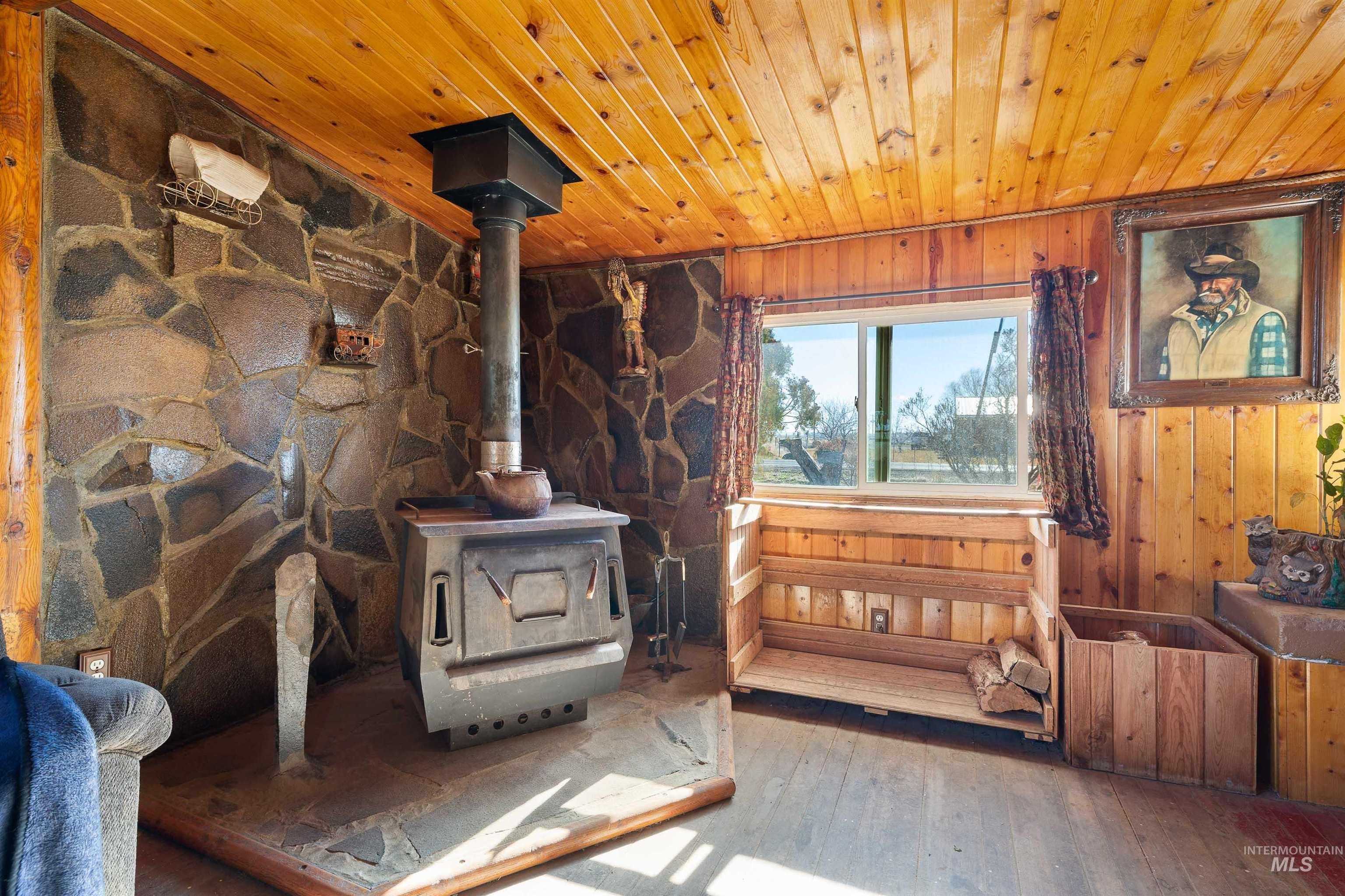 1898 East 3700th Street North Filer, ID 83328 - Photo 4 of 40 Living room with a wood stove, wooden ceiling, wood-type flooring, and wooden walls