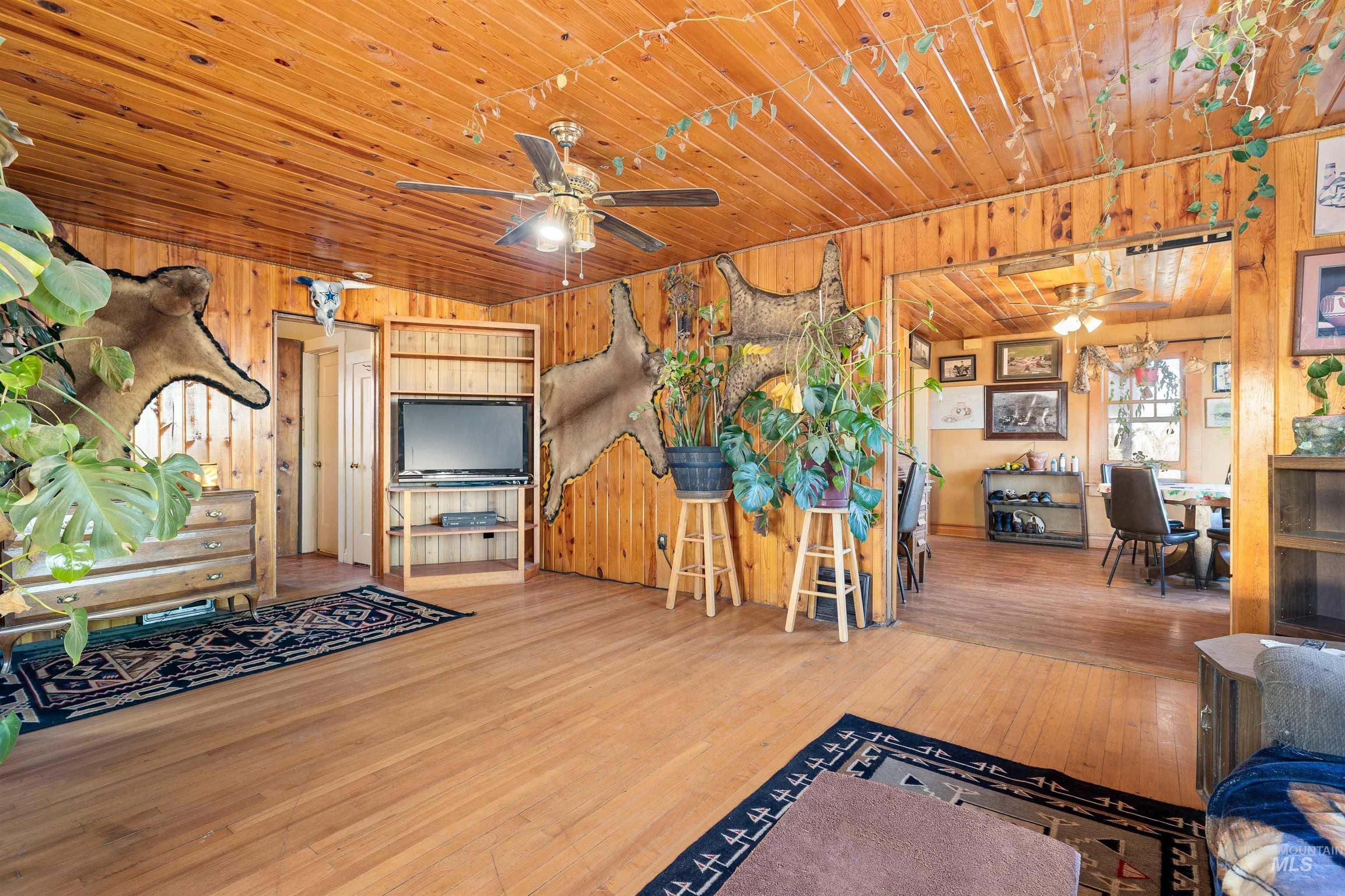 1898 East 3700th Street North Filer, ID 83328 - Photo 6 of 40 Living room featuring ceiling fan, hardwood / wood-style floors, wooden ceiling, and wooden walls