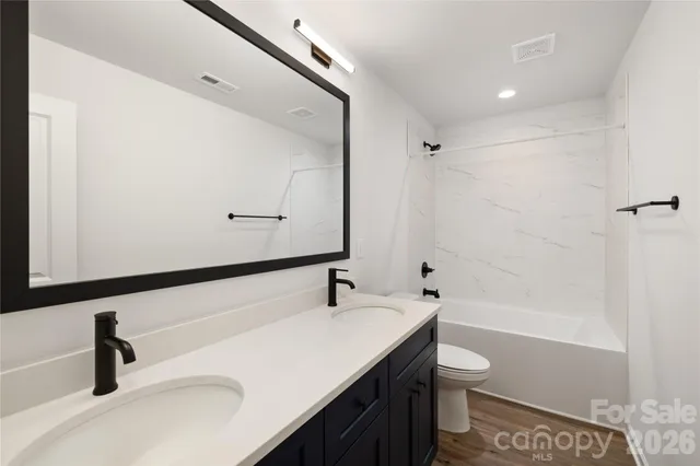 a bathroom with a sink a toilet a mirror and shower