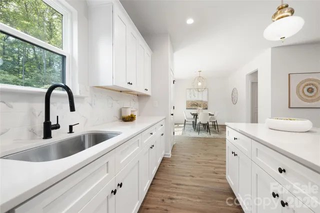 a large white kitchen with sink and white cabinets