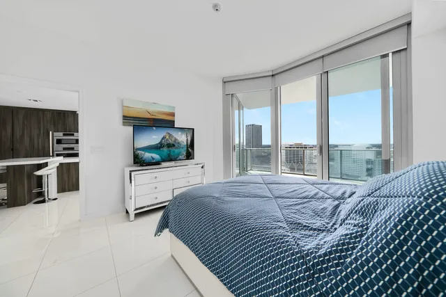 a bedroom with a large bed and a flat tv screen on dresser