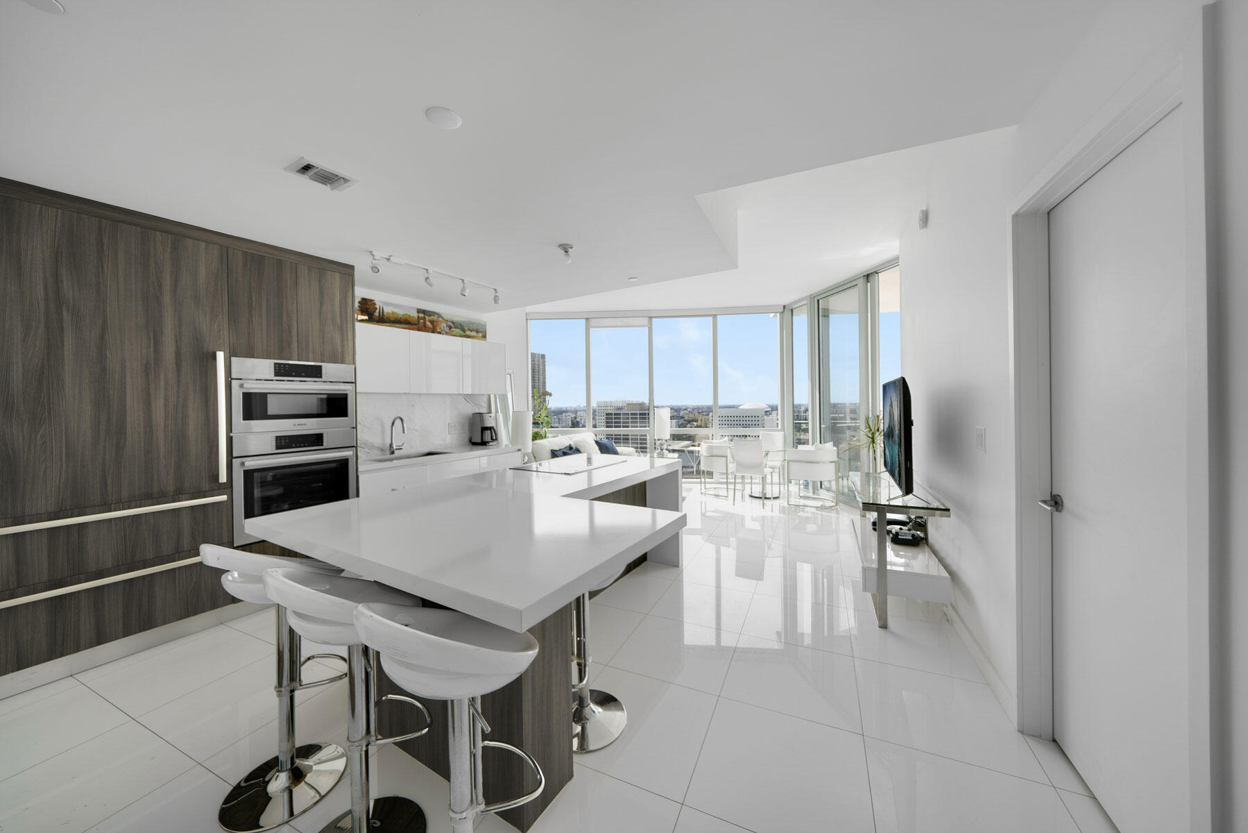 851 Northeast 1st Avenue, Unit 2410 Miami, FL 33132 - Photo 3 of 27 a kitchen with a table chairs refrigerator and cabinets