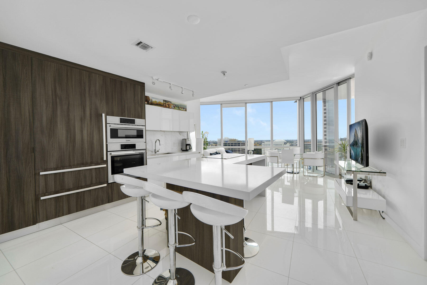 851 Northeast 1st Avenue, Unit 2410 Miami, FL 33132 - Photo 4 of 27 a large white kitchen with a sink and chairs