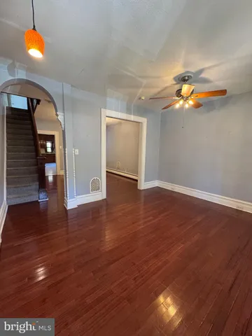 a view of an empty room with wooden floor and windows