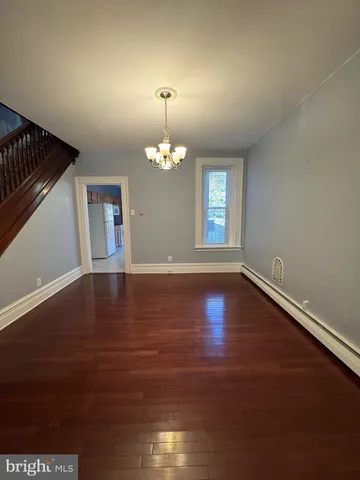 an empty room with wooden floor chandelier fan and windows