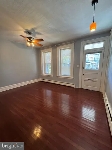 an empty room with wooden floor fan and windows