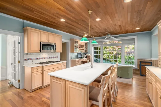 a open kitchen with stainless steel appliances granite countertop a stove a refrigerator a microwave oven with a dining table and chairs with wooden floor