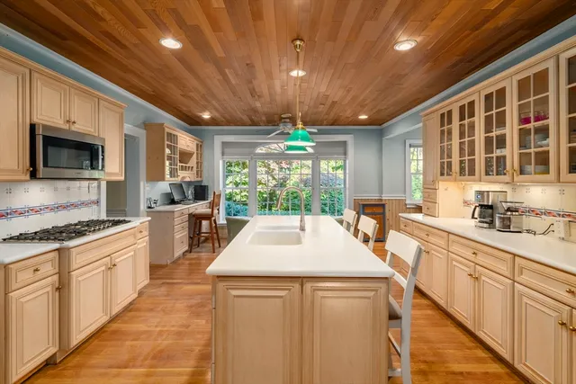 a kitchen with kitchen island granite countertop a stove a sink dishwasher and white cabinets with wooden floor