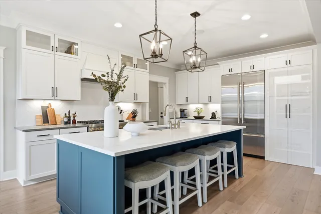 a kitchen with stainless steel appliances kitchen island granite countertop a sink a stove a refrigerator and island with wooden floor