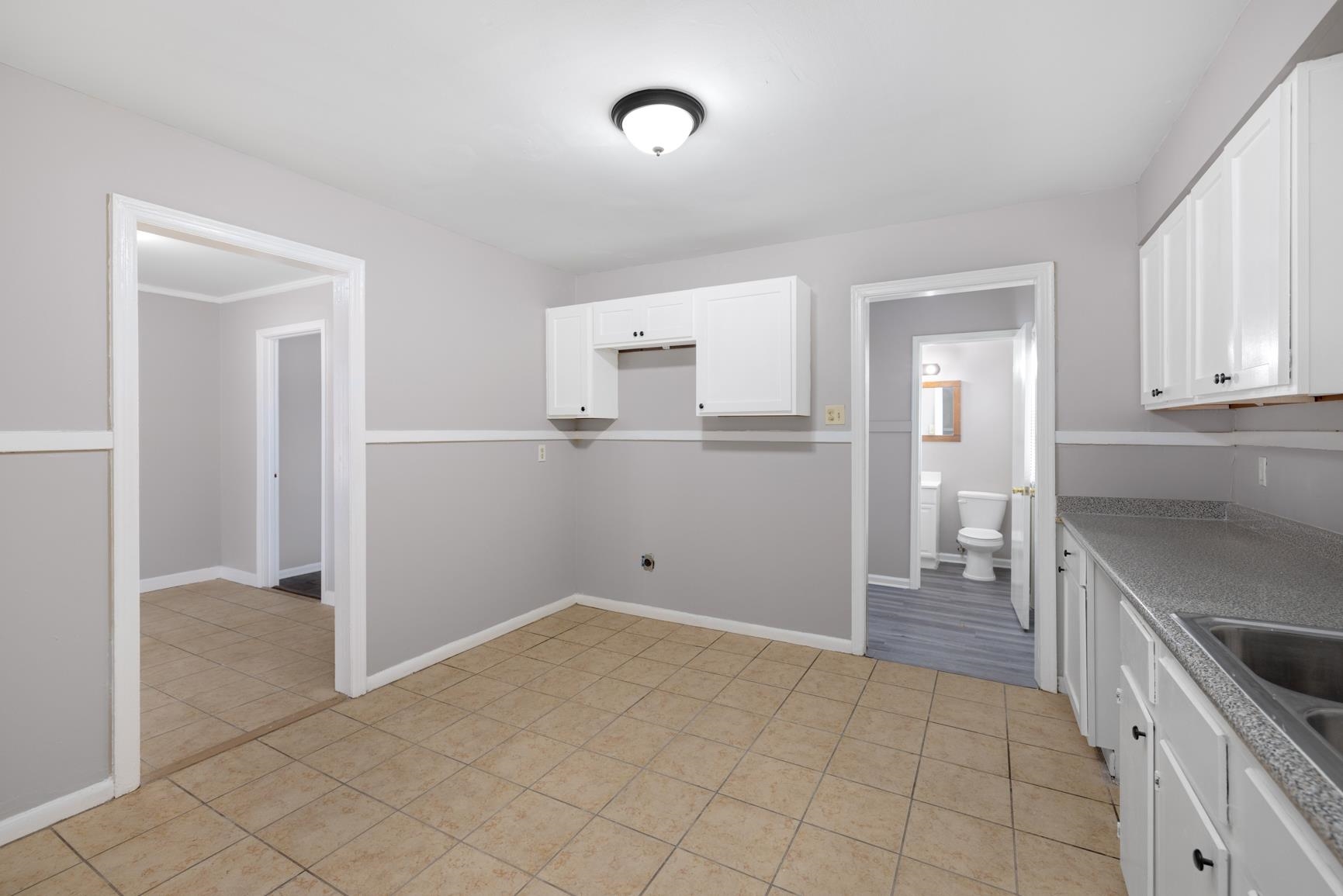 1584 South Perkins Road Memphis, TN 38117 - Photo 12 of 21 Kitchen with light tile patterned floors, white cabinets, baseboards, and a sink