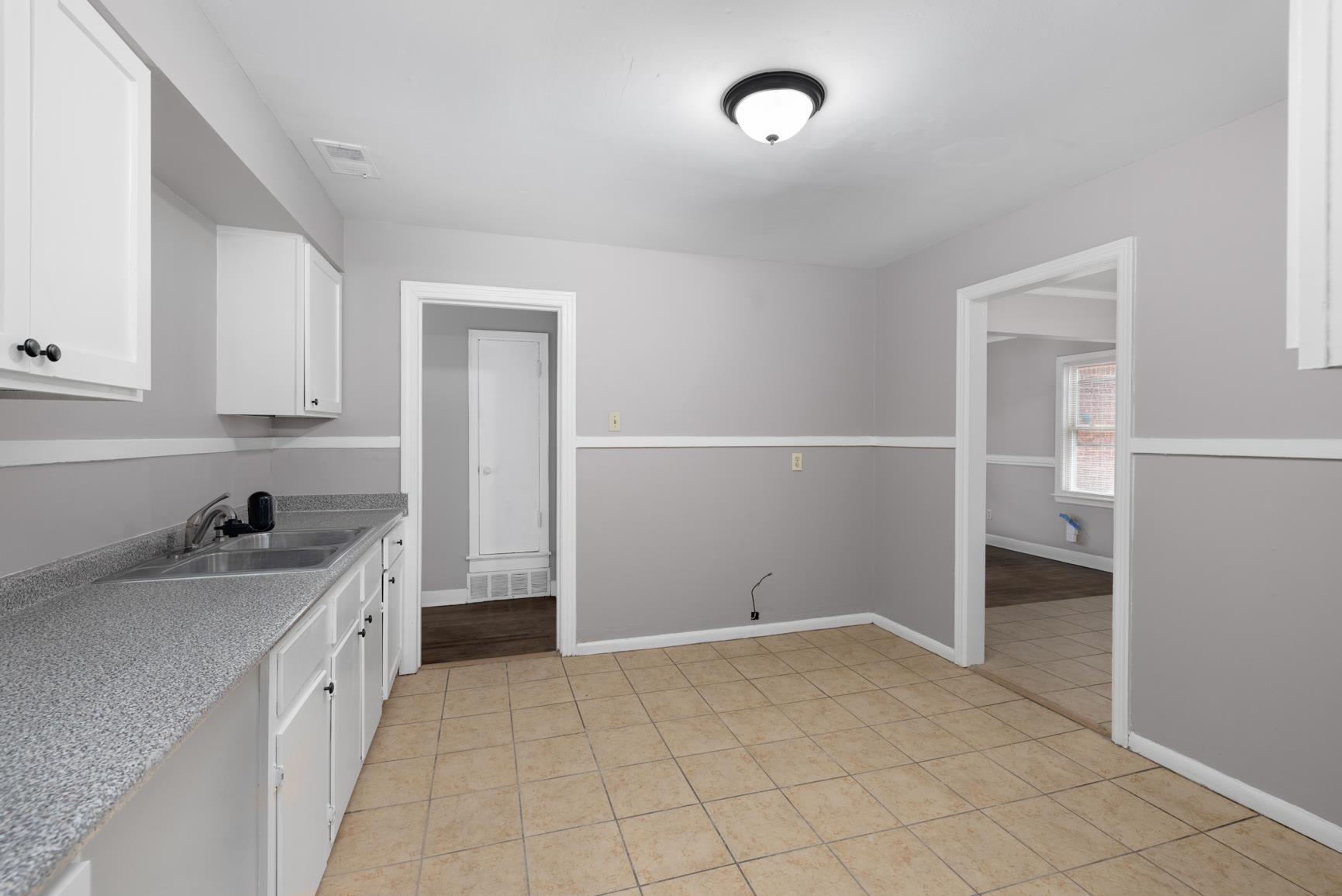 1584 South Perkins Road Memphis, TN 38117 - Photo 13 of 21 Kitchen with light tile patterned floors, visible vents, a sink, light countertops, and white cabinetry