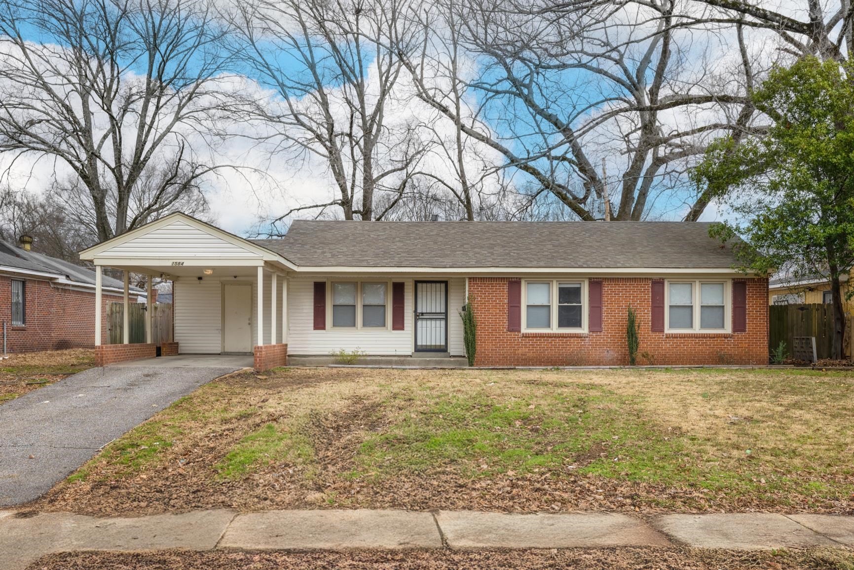 1584 South Perkins Road Memphis, TN 38117 - Photo 2 of 21 Ranch-style home with an attached carport, fence, a front lawn, aphalt driveway, and brick siding