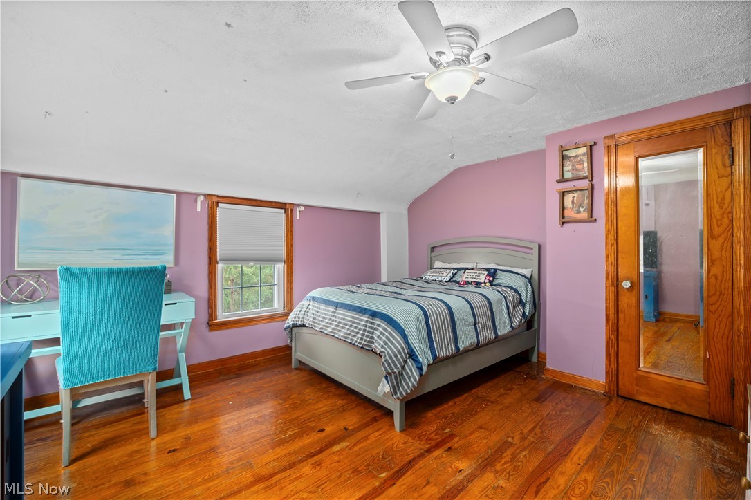 27258 Cook Road Olmsted Falls, OH 44138 - Photo 16 of 44 Hardwood flooring, ceiling fan with light fixture, window with roller shade, and a wood-paneled door with a full-length mirror