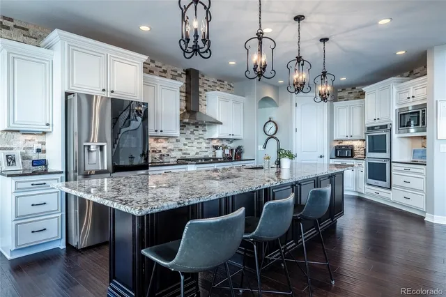 a kitchen with stainless steel appliances granite countertop a kitchen island a stove a table and chairs in it