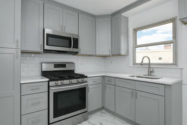 a kitchen with white cabinets appliances and a sink