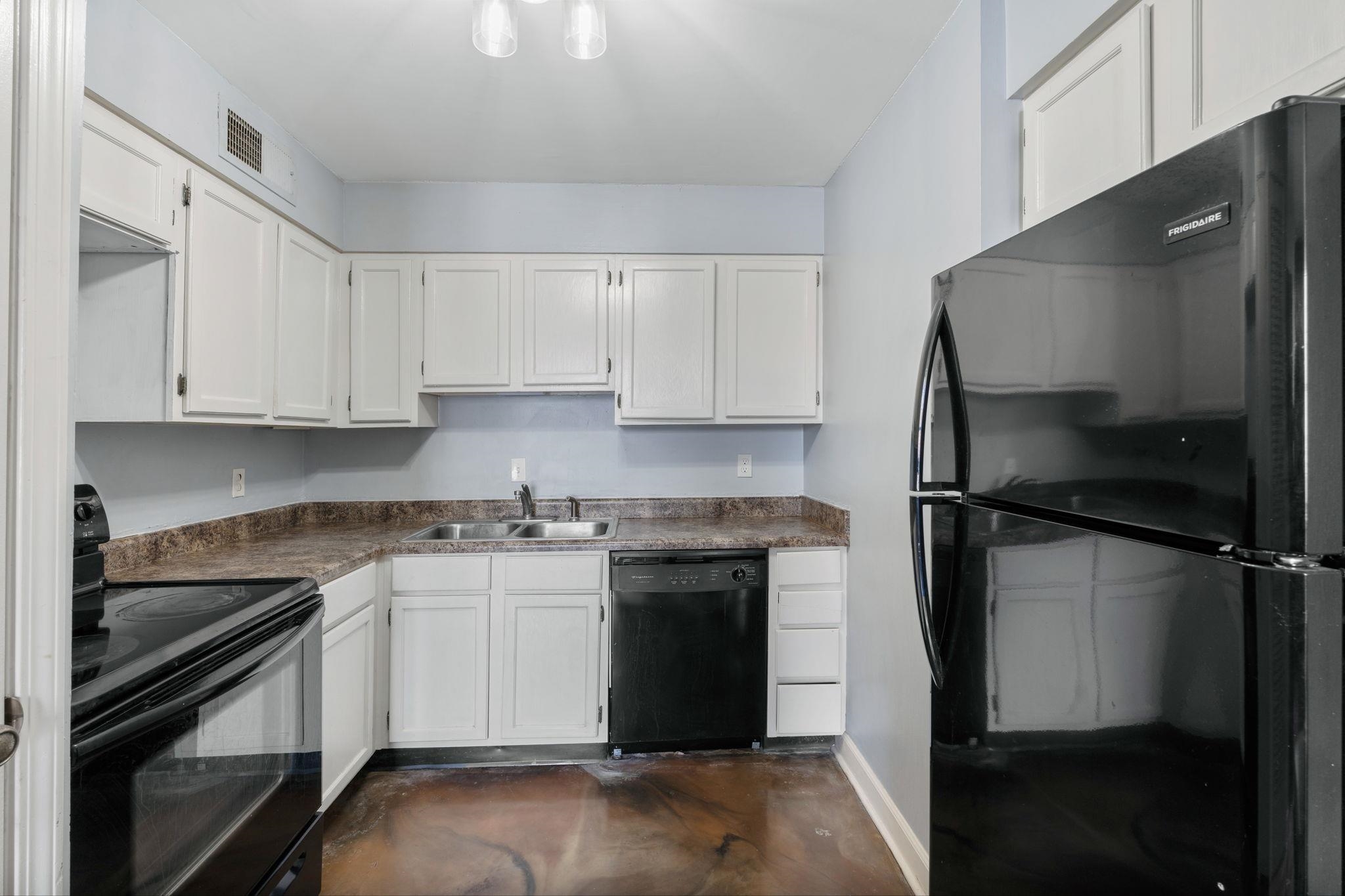 109 North Main Street, Unit 710 Memphis, TN 38103 - Photo 14 of 37 Kitchen with black appliances, concrete floors, white cabinetry, and dark countertops
