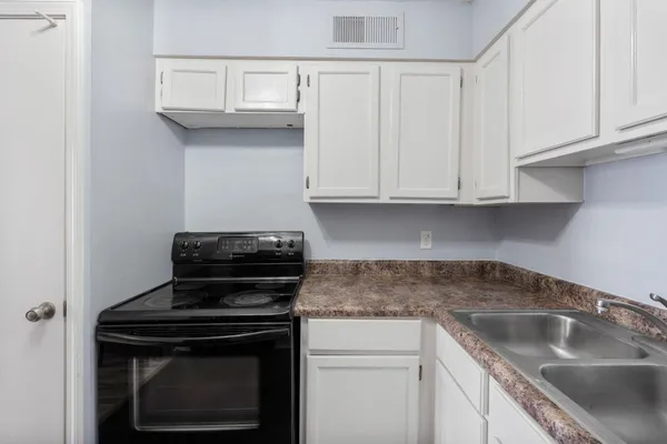a kitchen with granite countertop white cabinets and a stove top oven