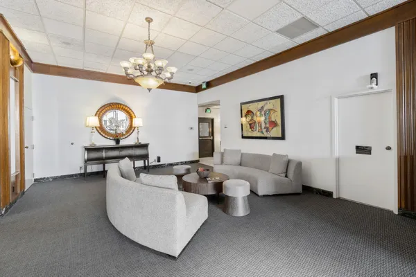 a living room with couches a chandelier and a clock