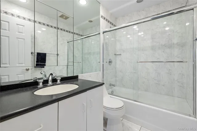 a bathroom with a sink a toilet a mirror and shower