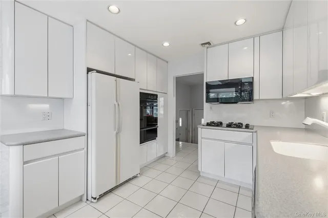 a kitchen with granite countertop white cabinets and stainless steel appliances