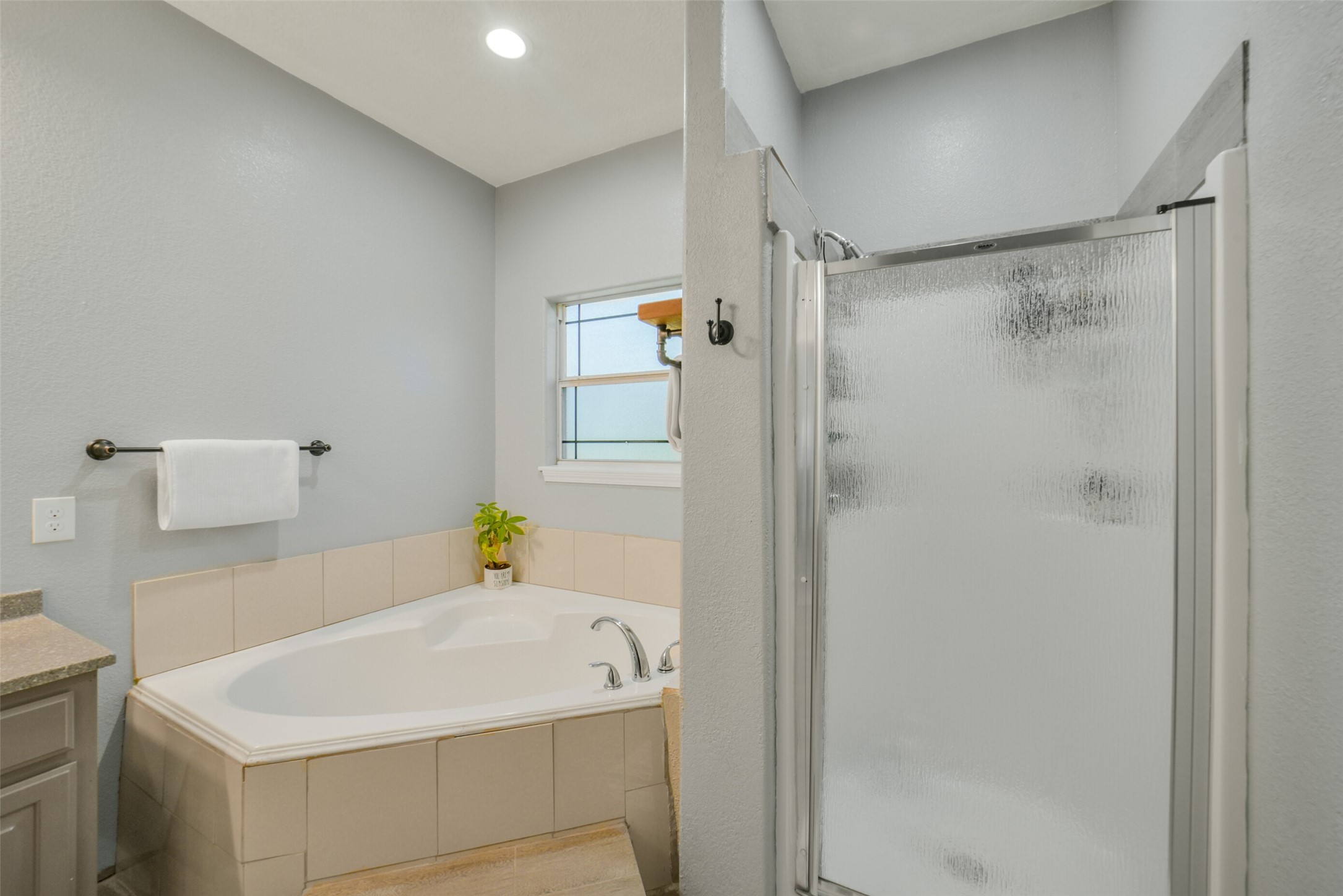 11301 South FM 441 Road El Campo, TX 77437 - Photo 21 of 43 This bathroom features a spacious corner bathtub, a separate frosted glass shower, modern fixtures, neutral tile and paint.