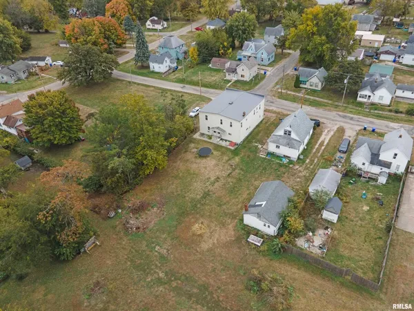 an aerial view of a house with swimming pool and large trees