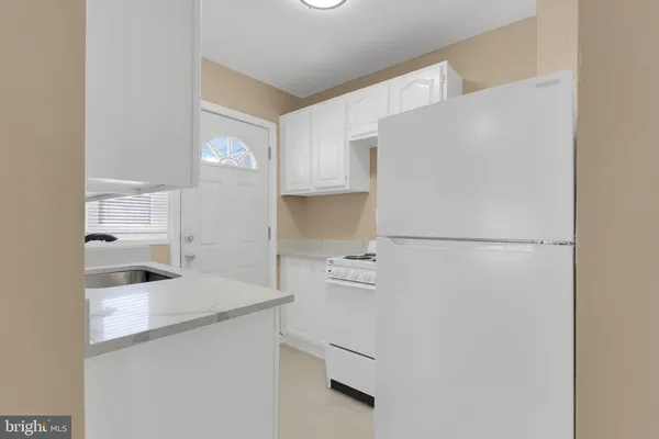 a kitchen with white cabinets and refrigerator