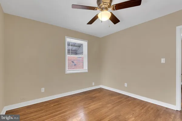 an empty room with wooden floor and chandelier fan