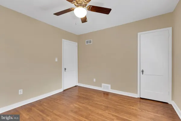 an empty room with wooden floor and a ceiling fan