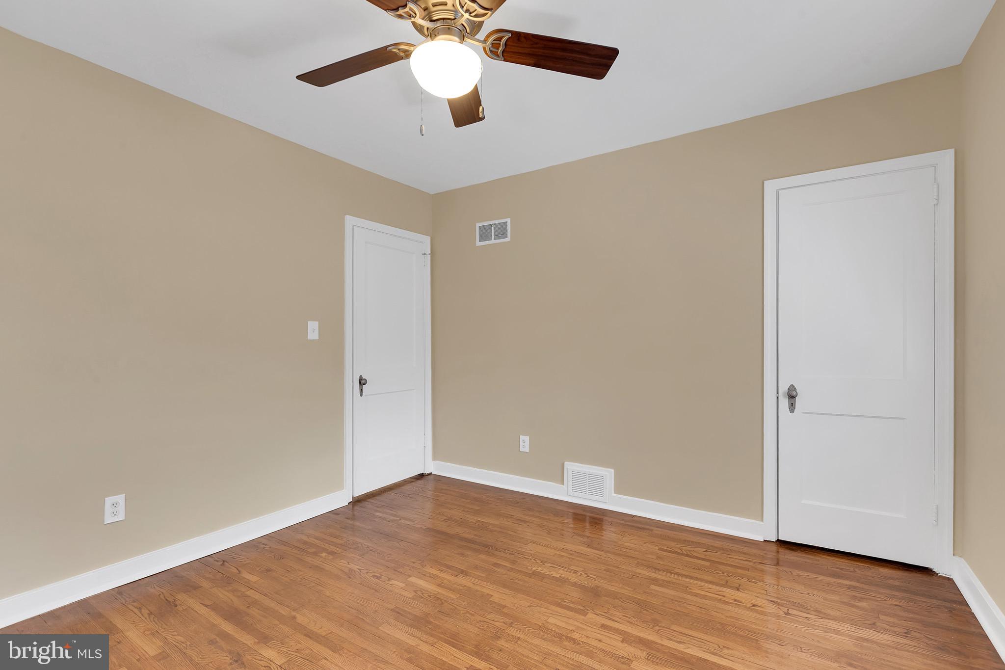 151 Darrington Street Southwest Washington, DC 20032 - Photo 5 of 22 an empty room with wooden floor and a ceiling fan