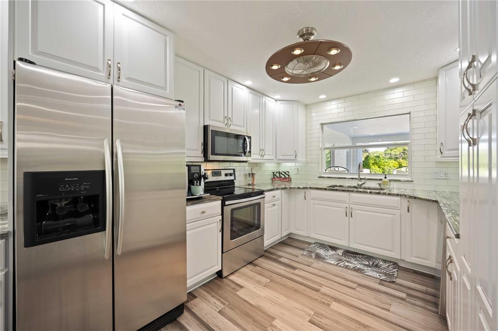 5025 Marsh Field Road Sarasota, FL 34235 - Photo 14 of 69 a kitchen with granite countertop stainless steel appliances a stove refrigerator and microwave