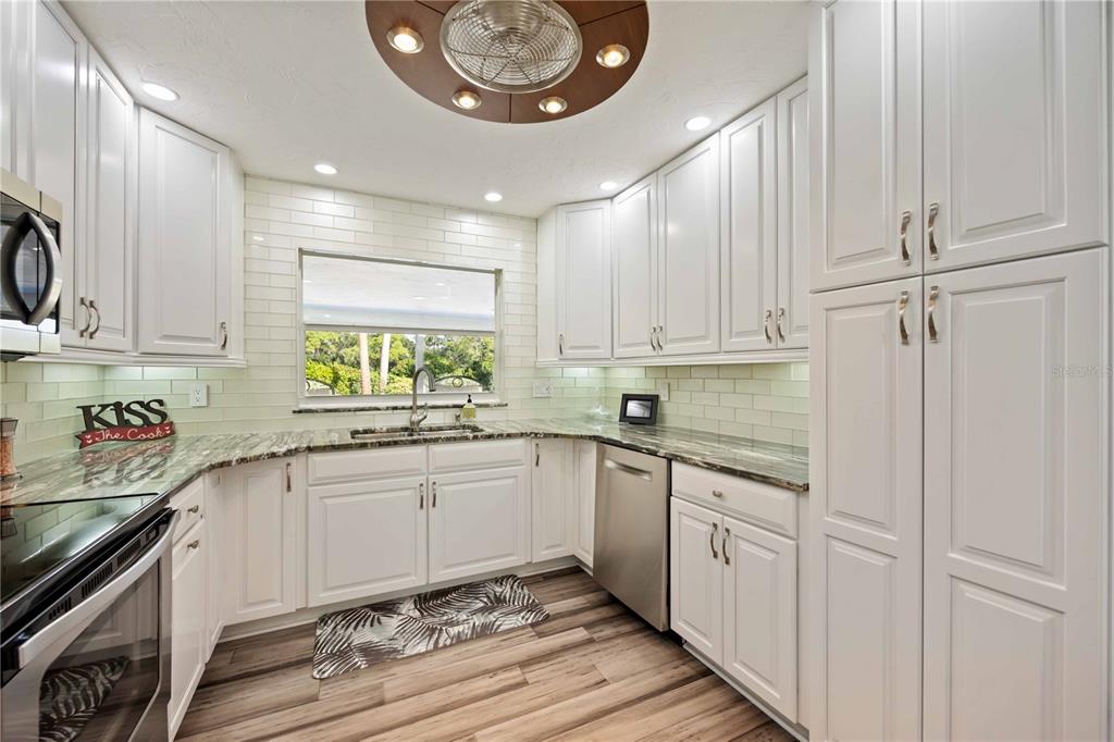 5025 Marsh Field Road Sarasota, FL 34235 - Photo 16 of 69 a kitchen with granite countertop white cabinets and stainless steel appliances